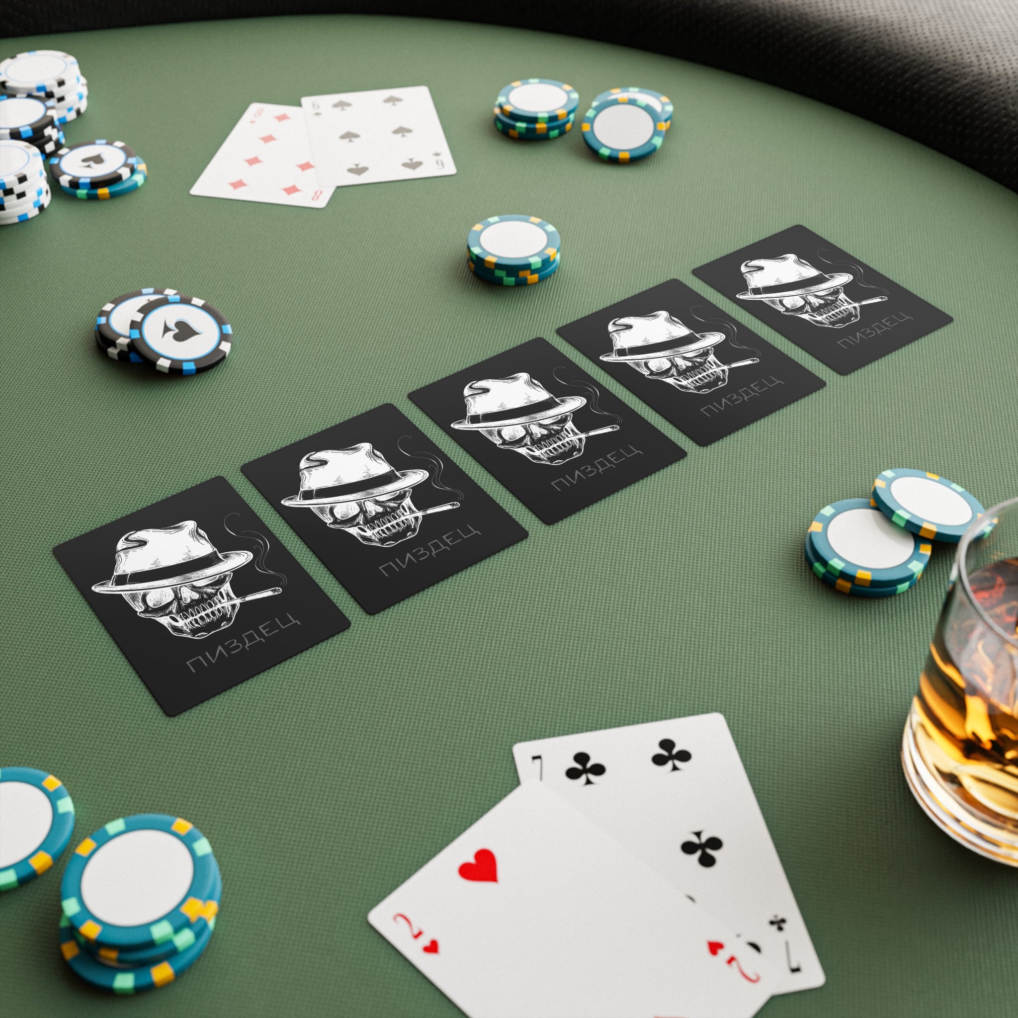 Pokertisch mit Pisdez Pokerkarten, es liegen chips auf dem Tisch und ein Glas mit einem Getränk, es liegen 4 Karten aufgedeckt 2 Herz und 7 Kreuz 